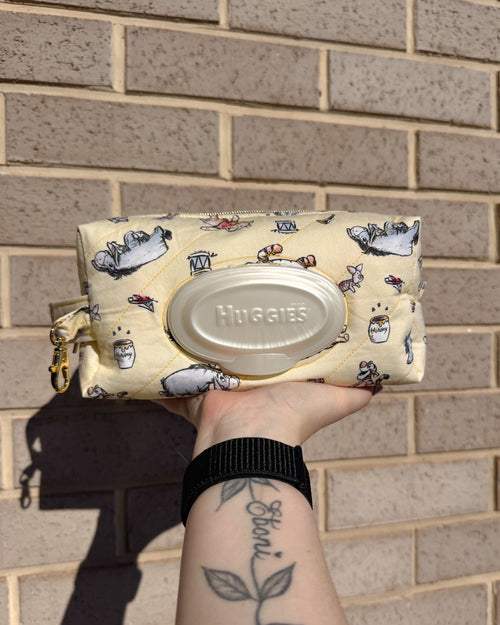 Huggies wipes container in a patterned pouch held against a brick wall