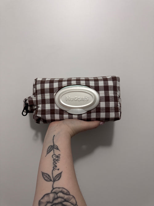 Huggies wipes case with plaid pattern held by a person against a plain background