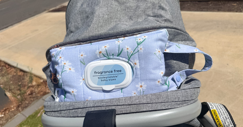 Baby carrier with a blue floral-patterned cover on a sidewalk