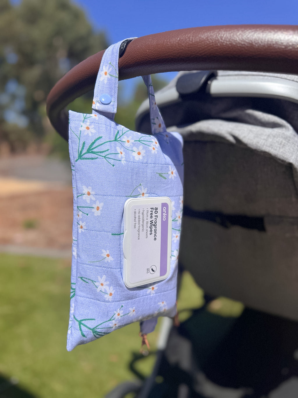 Wet wipes pouch with floral design hanging from a stroller handle