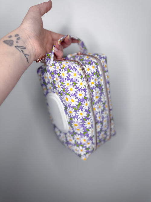 Hand holding a floral-patterned bag against a plain background