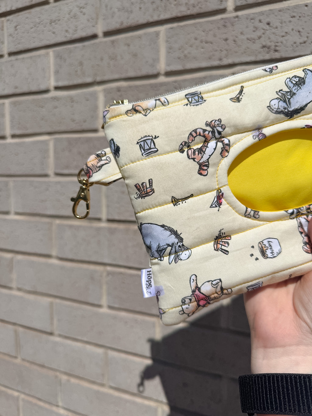 Small pouch with cartoon character pattern held against a brick wall