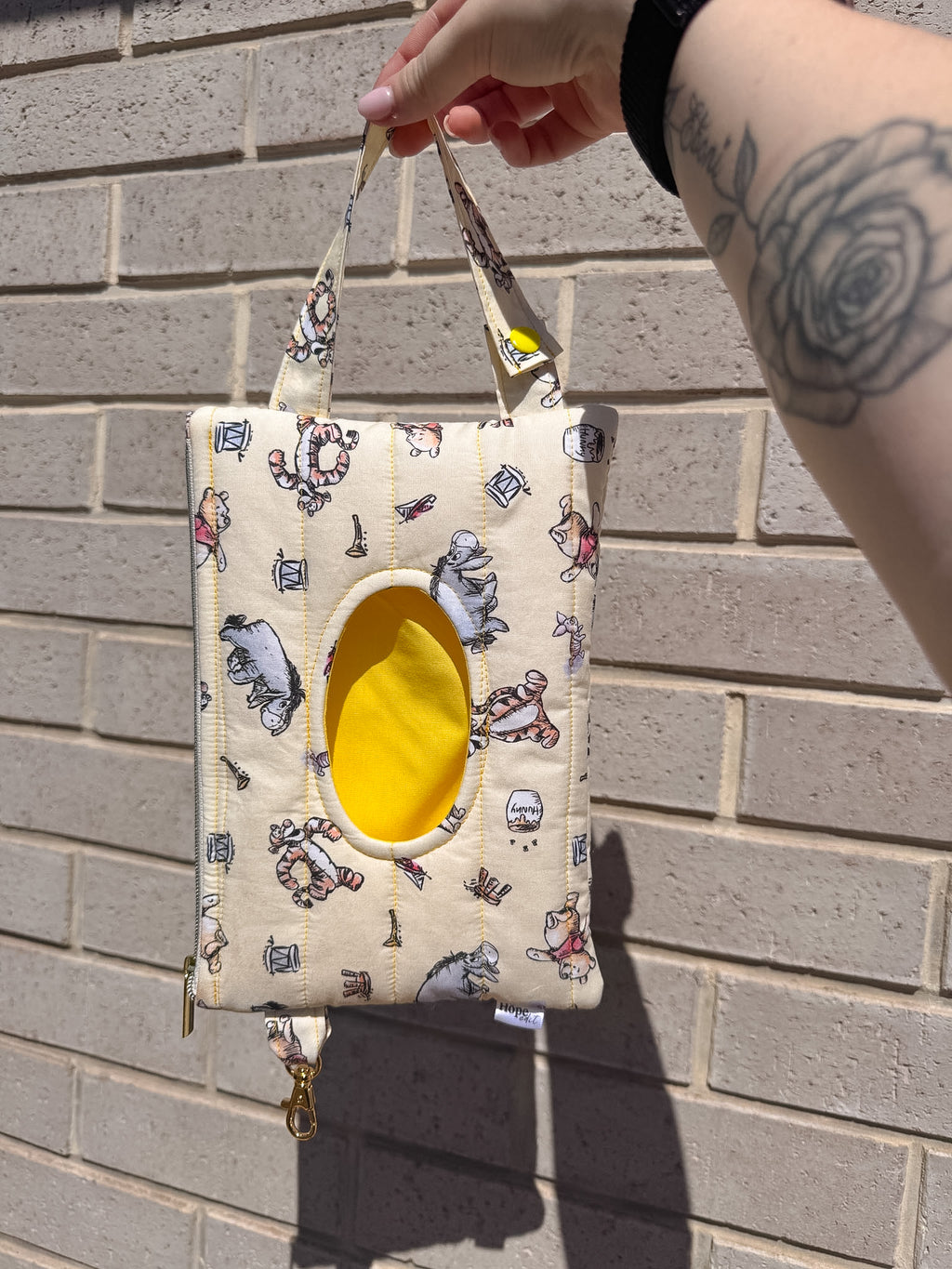 Small pouch with cartoon character pattern held against a brick wall