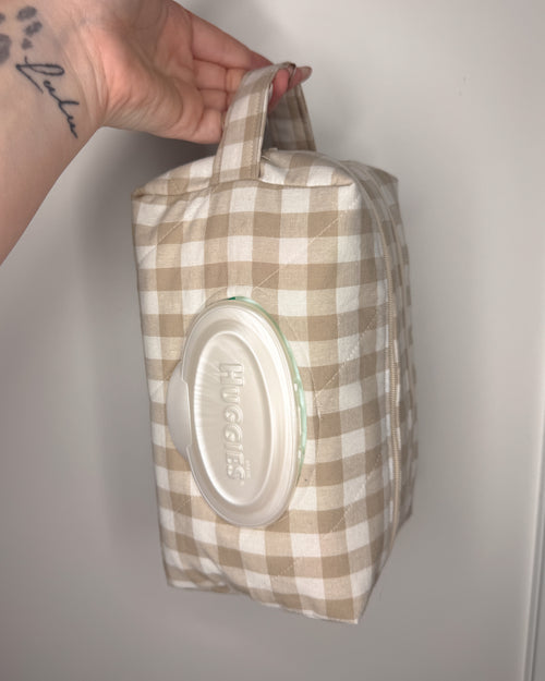 Checkered bag with a lid containing wipes on a plain background