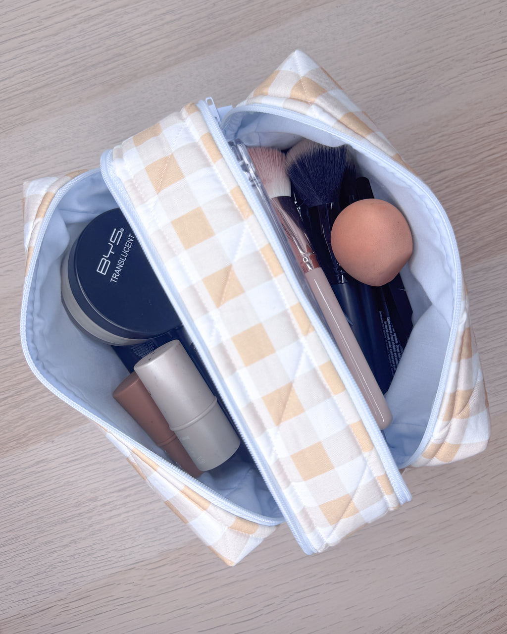 Makeup bag with cosmetic items on a wooden surface