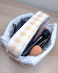 Makeup tools in a checkered container on a wooden surface